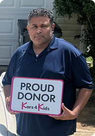 A person holding a sign that says Proud Donor Kars4Kids