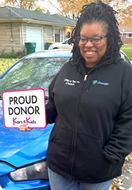A person holding a sign that says Proud Donor Kars4Kids